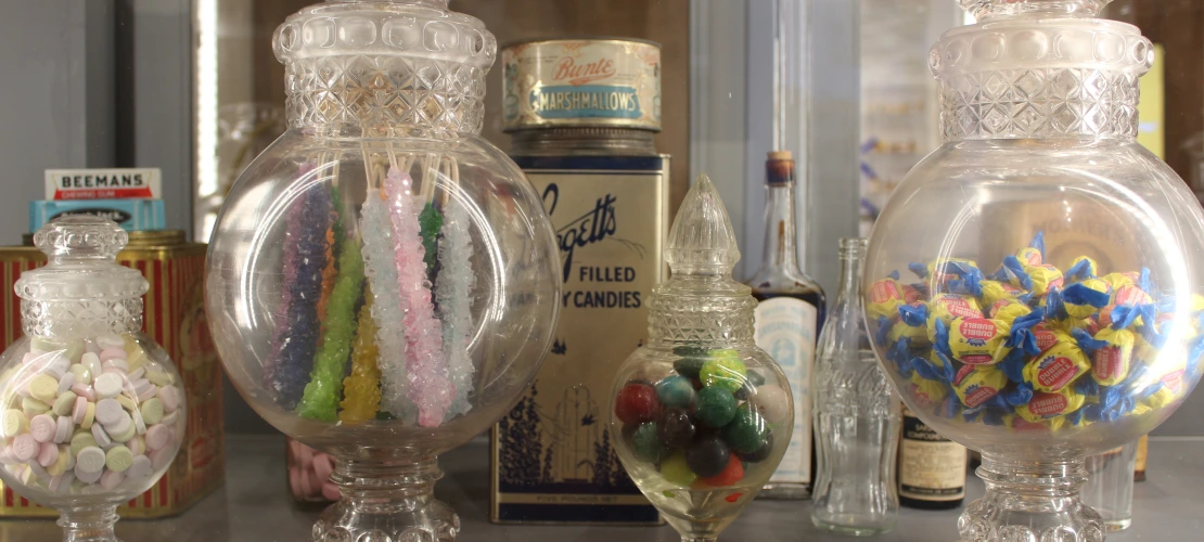 clear candy jars full of candy sit on a shelf