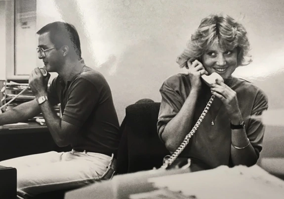 Two students, a man and woman, man phones during the 1987 UA College of Pharmacy in 1987. The woman holds a receiver and smiles as she talks to a caller