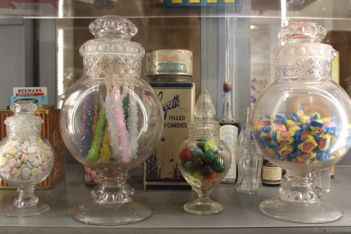 clear candy jars full of candy sit on a shelf